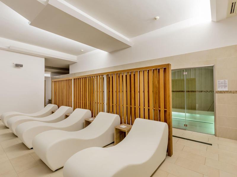 Espace bien-être moderne avec chaises longues blanches et cloison en bois à côté d'une section en verre.