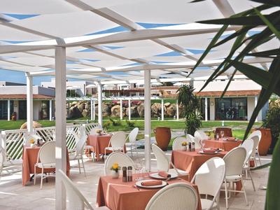 Freiluft-Restaurant mit orangefarbenen Tischdecken und weißen Stühlen unter einer Pergola.