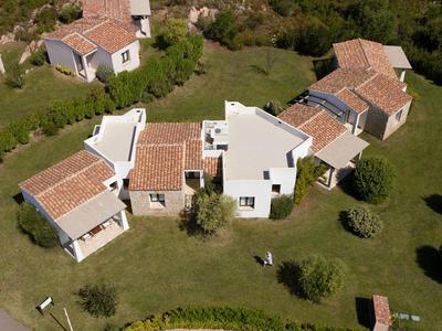 Luftaufnahme eines Hauses mit roten Ziegeldächern und umgeben von grünem Rasen und Sträuchern