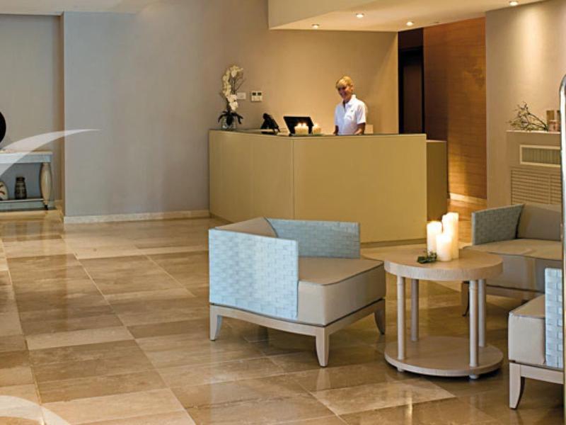 Moderne Lobby mit beigem Marmorfußboden, blauen Sitzmöbeln und goldfarbenem Empfangstresen.