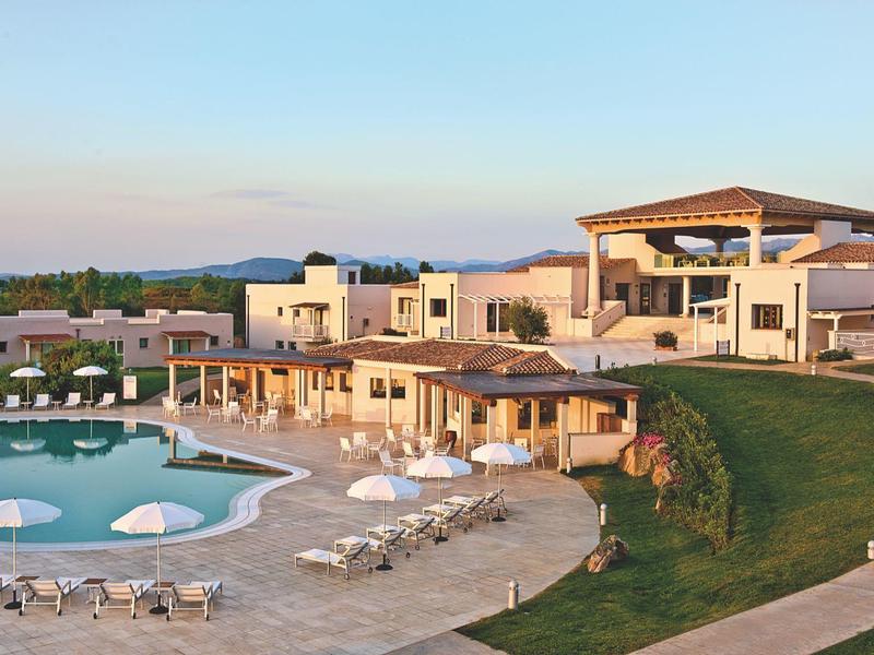 Luxuriöse Resortanlage mit Pool, Liegestühlen und moderner Architektur bei Sonnenuntergang.