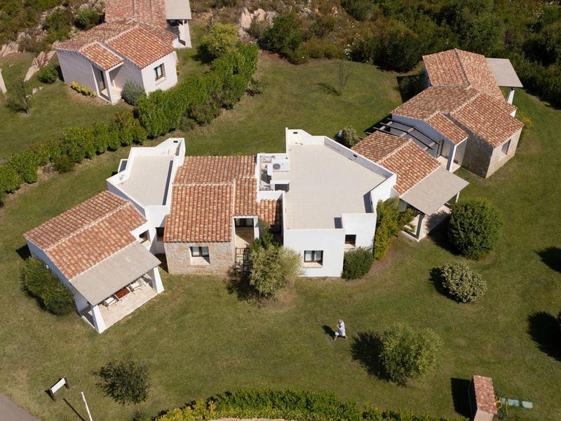 Luftaufnahme eines Hauses mit roten Ziegeldächern und großem Garten in grüner Umgebung.