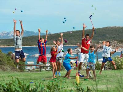 Gruppo di bambini che saltano e lanciano cappelli vicino al mare in una giornata di sole.