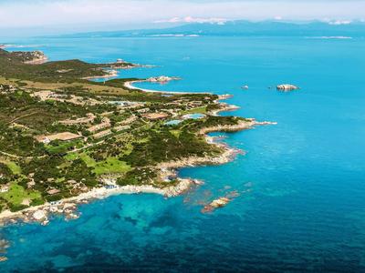 Veduta aerea di una costa rocciosa con vegetazione verde e acqua azzurra limpida.