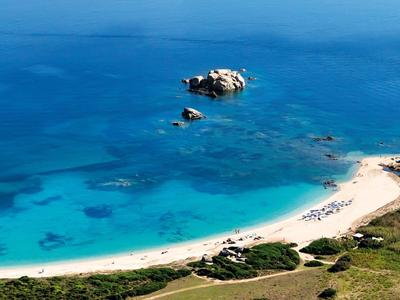 Mare blu chiaro con spiaggia di sabbia bianca e piccole rocce vicino alla costa.