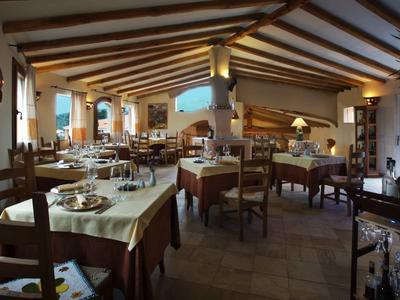 Lichte eetzaal met houten balkenplafond, tafels met witte tafelkleden en houten stoelen.