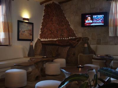 Accogliente sala con camino rivestito in pietra, sedute imbottite e soffitto con travi in legno.