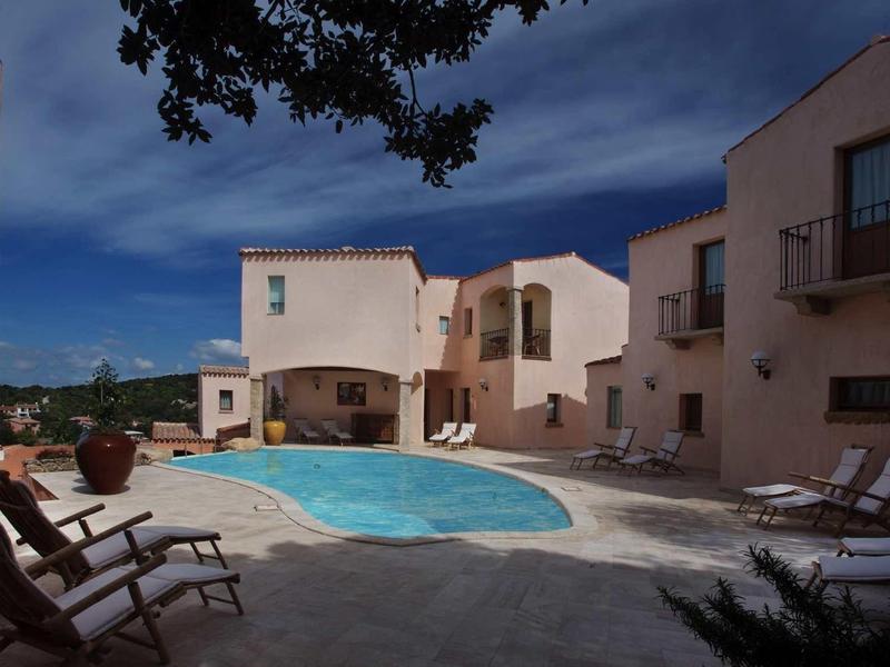 Hotelcomplex met zwembad omgeven door twee- tot drielaagse gebouwen onder een donkere lucht.