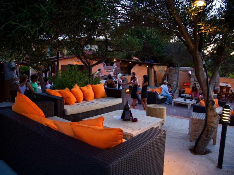 Comodi posti a sedere moderni con cuscini arancioni sotto gli alberi all'aperto.