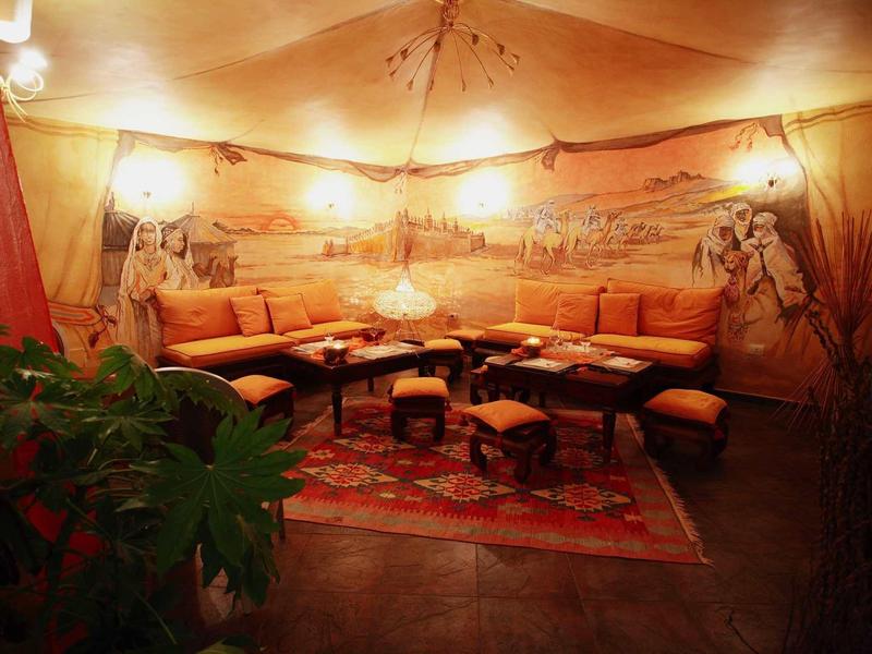 Lounge accogliente con posti a sedere rotondi, luce calda e murale orientale.