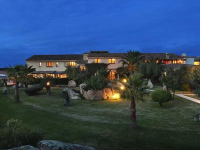 Luxusní hotel s osvětlenými budovami a upravenou zahradou za soumraku