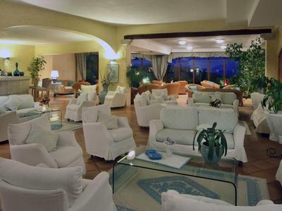 Prostorná hotelová hala s bílými křesly, stoly a nočním výhledem na verandu.