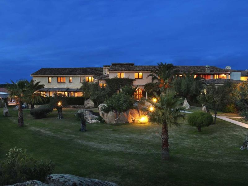 Luxusní hotel s osvětlenými budovami a upravenou zahradou za soumraku