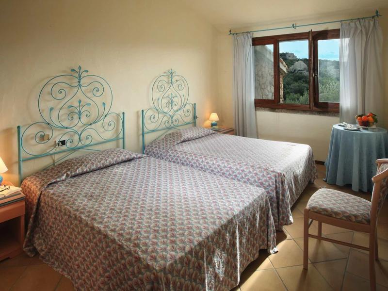 Hotelový pokoj se dvěma samostatnými lůžky, stolem s ovocem a otevřeným oknem s výhledem.