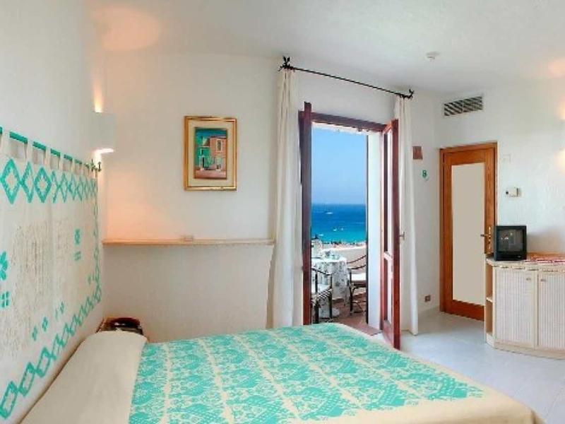 Camera luminosa con letto matrimoniale, vista mare dalla finestra e arredi semplici.