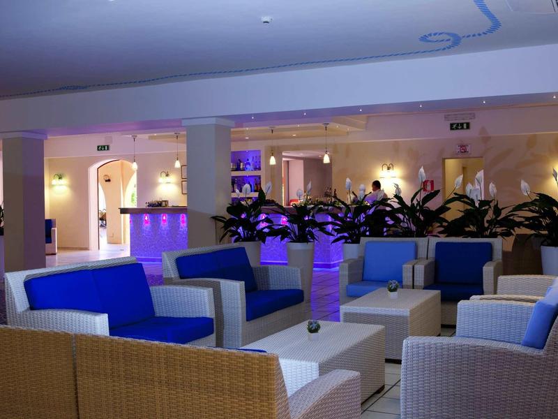 Moderne Hotellounge mit blauen und weißen Sofas, Tischen und farbiger Beleuchtung.