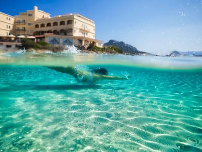 Vista a metà fuori e a metà sott'acqua di un hotel sul mare con acqua turchese limpida.