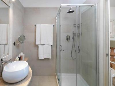 Modern hotel bathroom with glass shower, sink, and white towel.