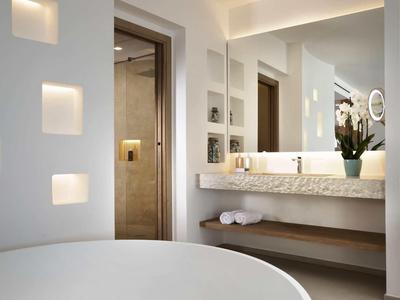 Modern hotel bathroom with large round bathtub and mirror wall with double sinks.
