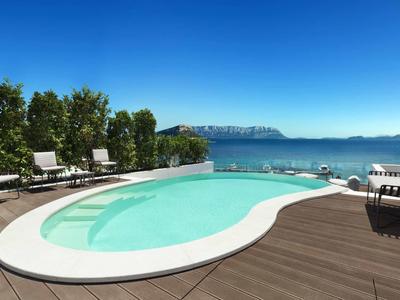 Round pool on wooden deck with view of sea and mountains under clear sky