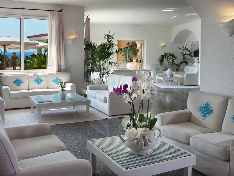 Bright living room with white furniture, blue accents, and pool view.