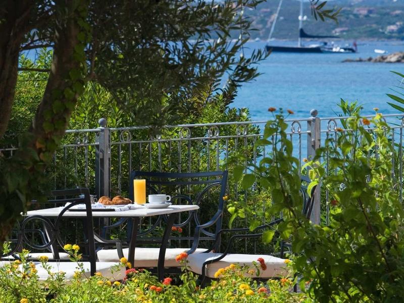 Table with juice glasses on terrace overlooking sea and boat.