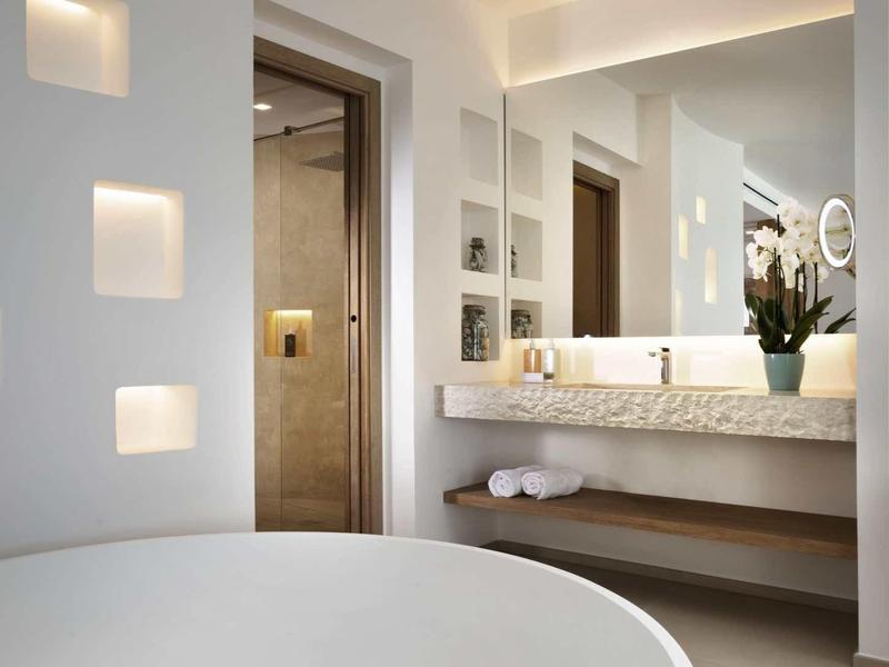 Modern hotel bathroom with large round bathtub and mirror wall with double sinks.
