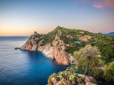 Coastline with rocky cliffs and blue sea at sunset.