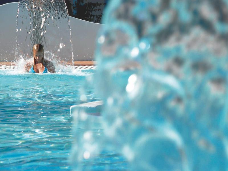 Relaxing pool scene with water fountains and a person enjoying the pool.