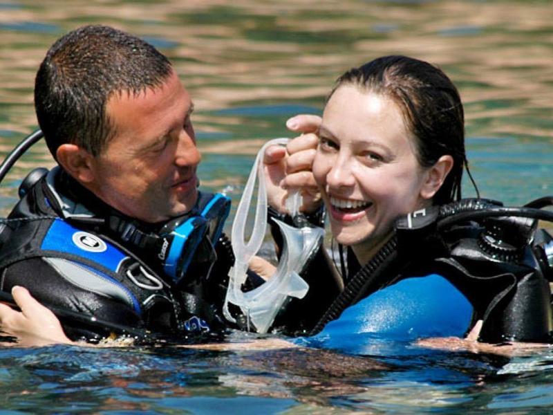 Couple in scuba gear smiling in water during diving lesson