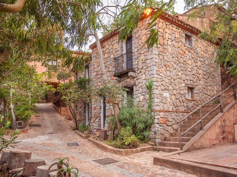 Charming stone house with plants along a paved path.