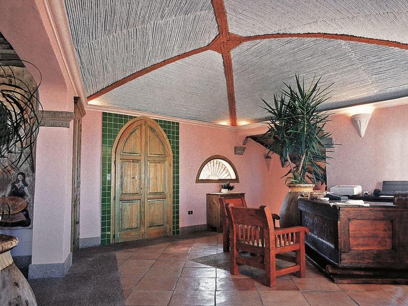 Innenraum mit rosa Wänden, hohen Decken, Holzmöbeln und einem großen grünen Türbogen.