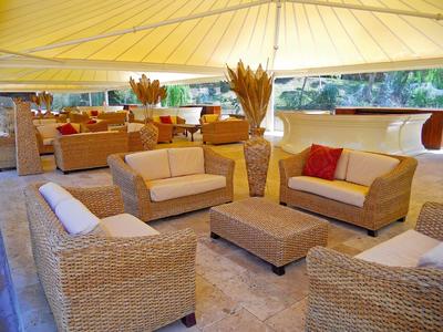 Área exterior acogedora de un hotel con muebles de mimbre y toldo amarillo.