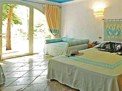 Habitación de hotel con dos camas, pisos de baldosas y puerta de vidrio hacia el exterior