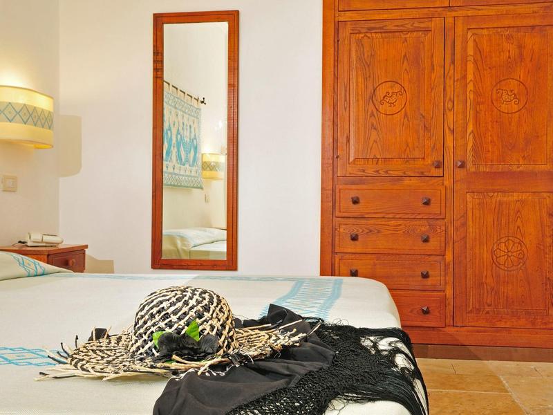 Dormitorio con muebles de madera, espejo grande y bufanda decorativa sobre la cama.