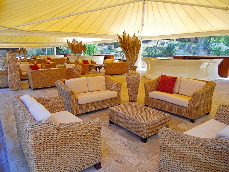 Área exterior acogedora de un hotel con muebles de mimbre y toldo amarillo.