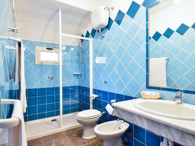 Moderne badkamer met douchecabine, toilet, bidet en blauwe tegels op muren en vloer.