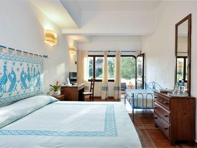 Licht ingericht hotelkamer met groot bed, houten kast en raam met uitzicht op groen