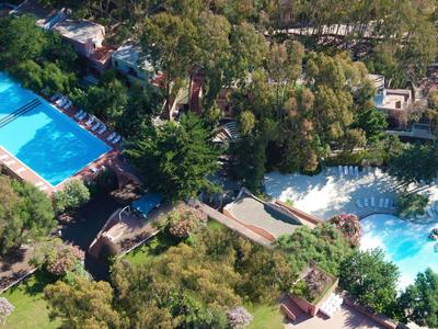 Luchtfoto van een hotelcomplex met zwembaden en veel groen.