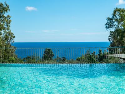 Vista di una piscina con il mare e un cielo azzurro limpido sullo sfondo.