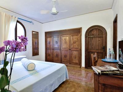 Lichte hotelkamer met groot bed, houten kast en bureau met waterflessen.