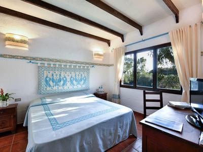 Gezellige slaapkamer met houten balken, groot raam en blauw-witte bedspreid.