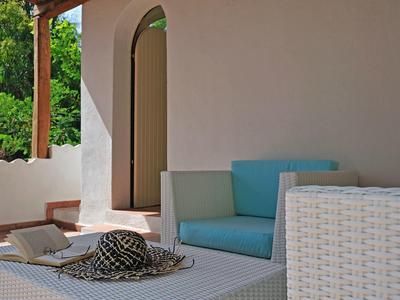 Moderne buitenruimte met wit vlechtwerkmeubilair, blauwe kussen en strohoed op tafel