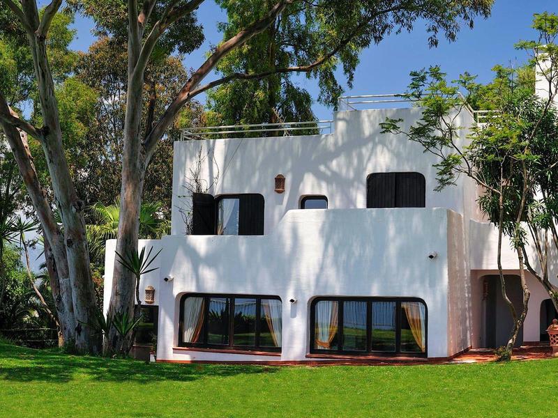 Wit huis met twee verdiepingen, zwarte raamkozijnen en een groen gazon op de voorgrond