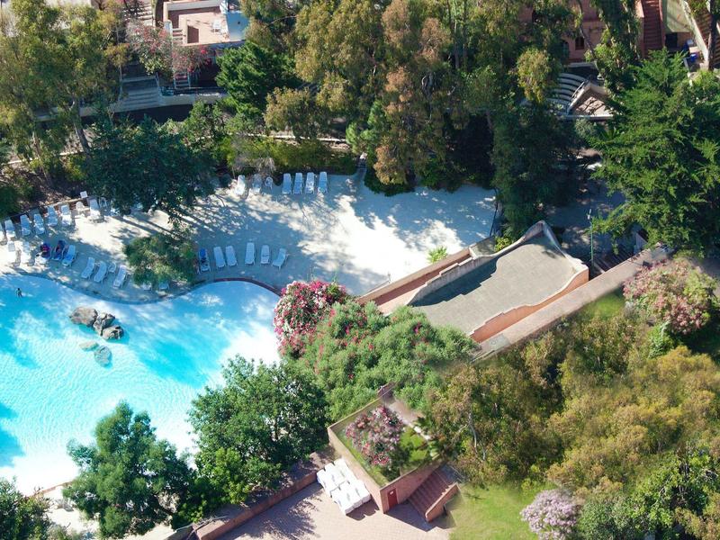 Luchtfoto van een hotelzwembad omringd door groen en ligstoelen.