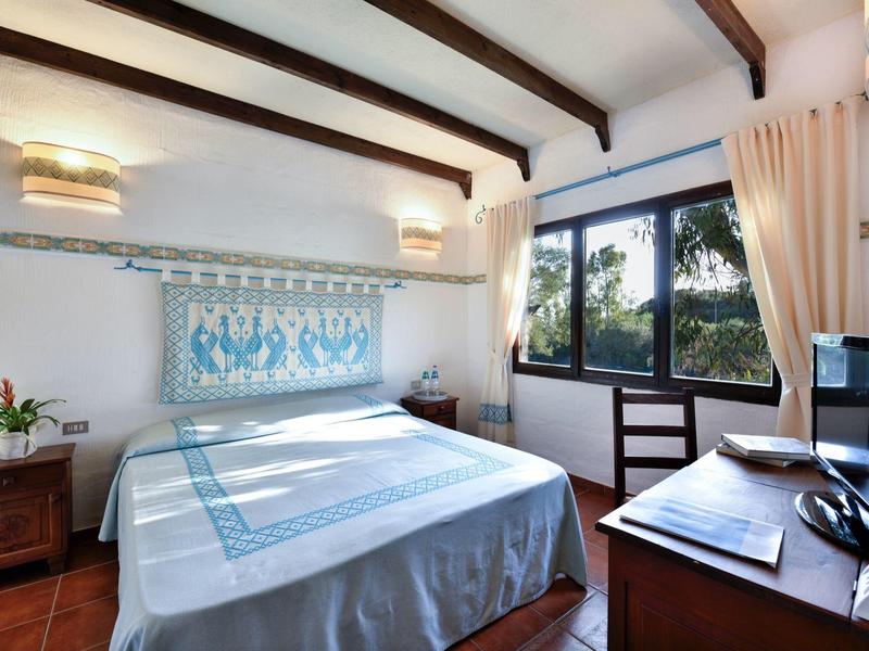 Gezellige slaapkamer met houten balken, groot raam en blauw-witte bedspreid.