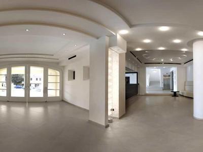 Grand hall d'hôtel lumineux avec canapé, comptoir et colonnes.