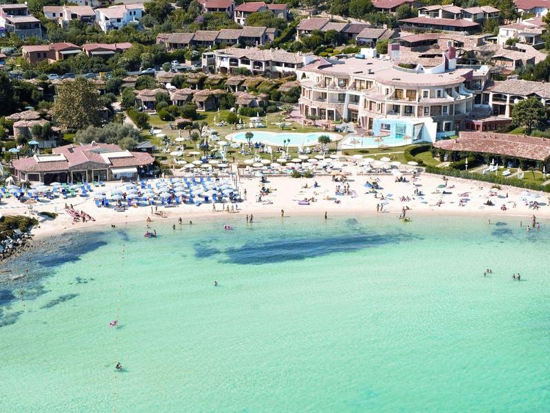 Spiaggia di sabbia bianca con acqua azzurra e edifici circostanti in una zona turistica