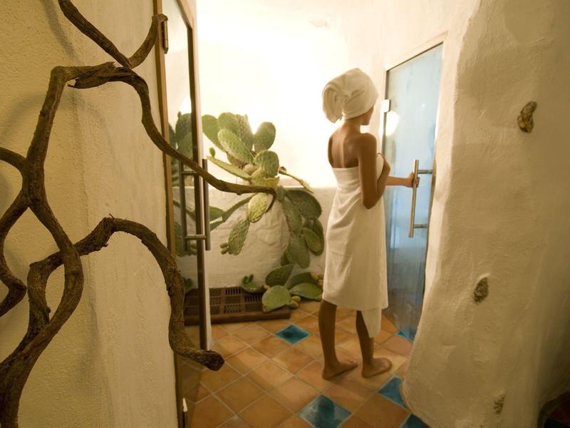 Donna con asciugamano in un bagno luminoso con forme organiche e piante.