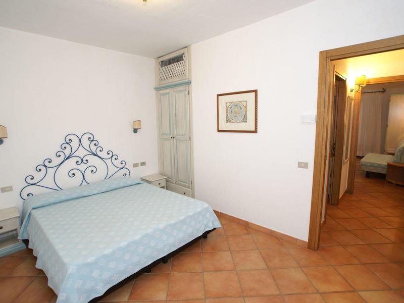 Camera d'hotel semplice con letto matrimoniale, pavimento in piastrelle e illuminazione soffusa.